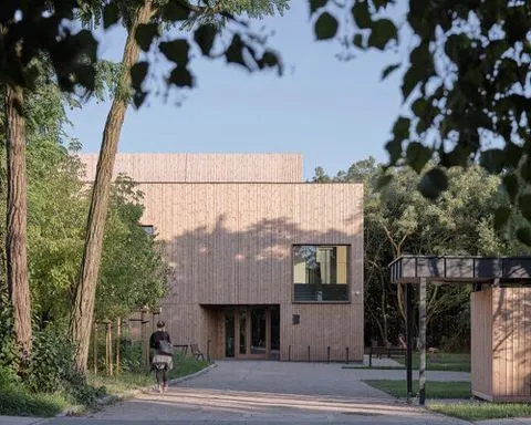 public library clad in washed timber integrates with warsaw’s wooded neighborhood