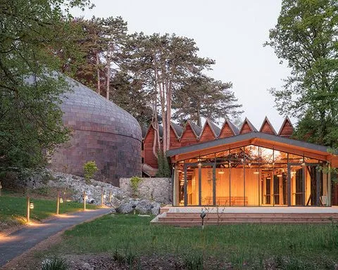 copper shingles wrap curving concert hall ‘la source vive’ in évian, france