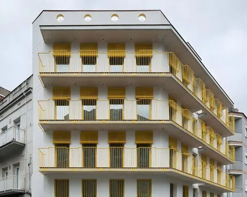 yellow steel, concrete, and circular openings revive corner building in spain as apart-hotel